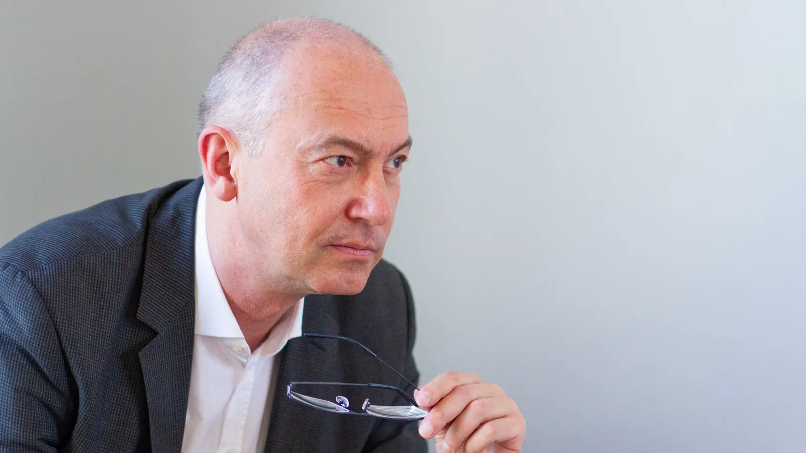 Reinhard Giese im Sakko, die Brille in der Hand, blickt nachdenklich zur Seite